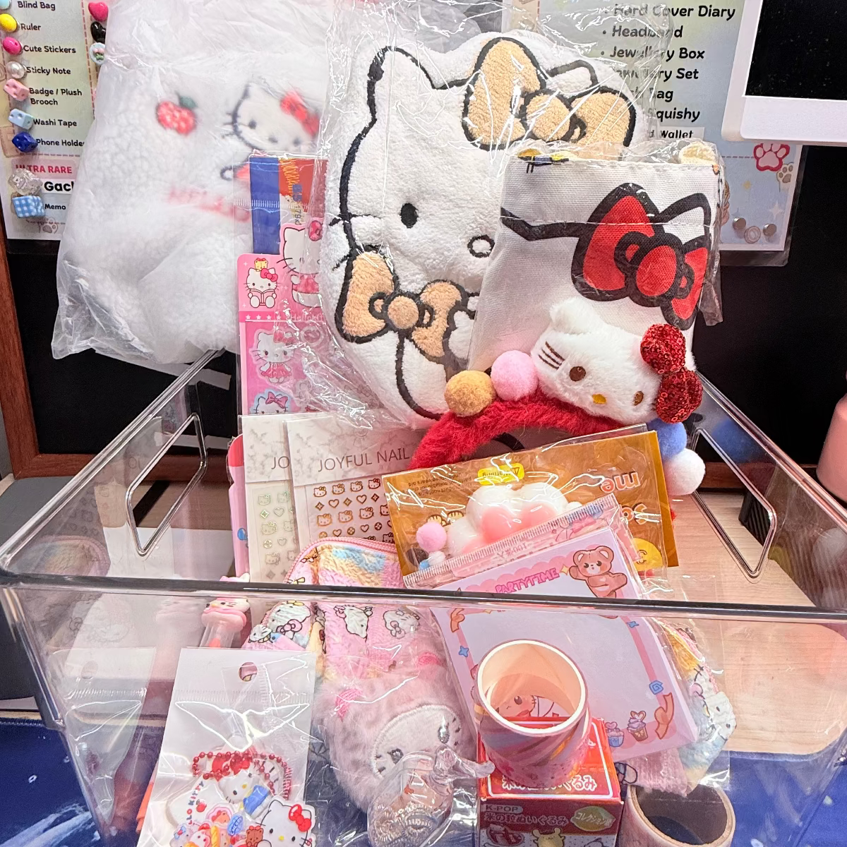 Get 20 Mystery Capsules in Hello Kitty Theme including makeup pouch, stamp,  nail stickers,  fairy headband, diary book, key charm. card holder, squishy, beaded pen, spray bottle, notebook, plush bag, hand towel and tote